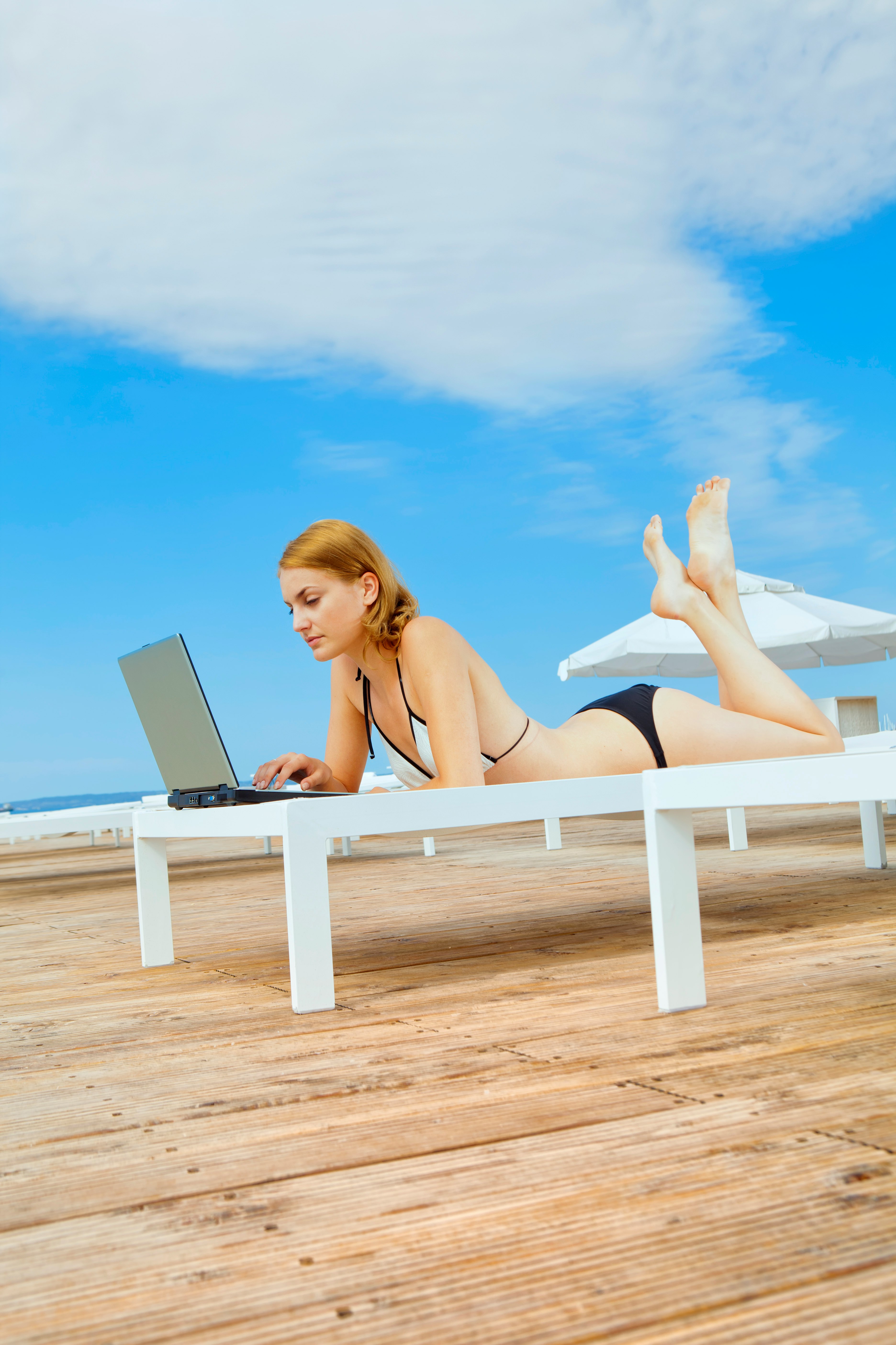woman in black bikini lying on white wooden bench